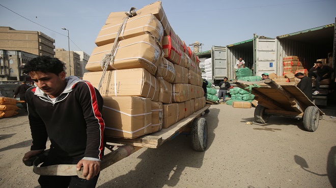عمال عراقيون يقومون بتفريغ البضائع المستوردة من شاحنة في حي الشورجة التجاري